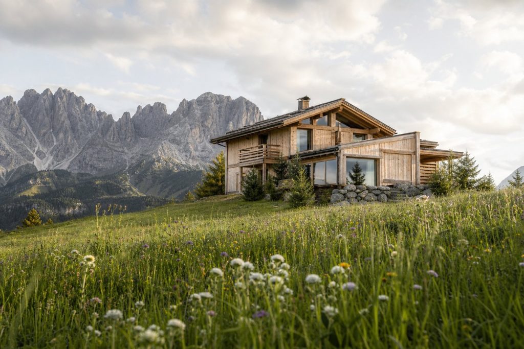 Chalet alpino in legno tra i prati con vista sulle Dolomiti