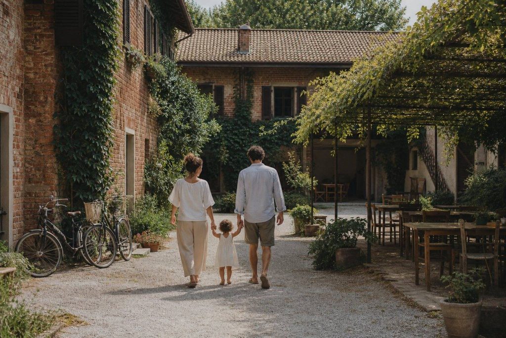 Cortile di una cascina milanese con tavoli in legno e famiglie
